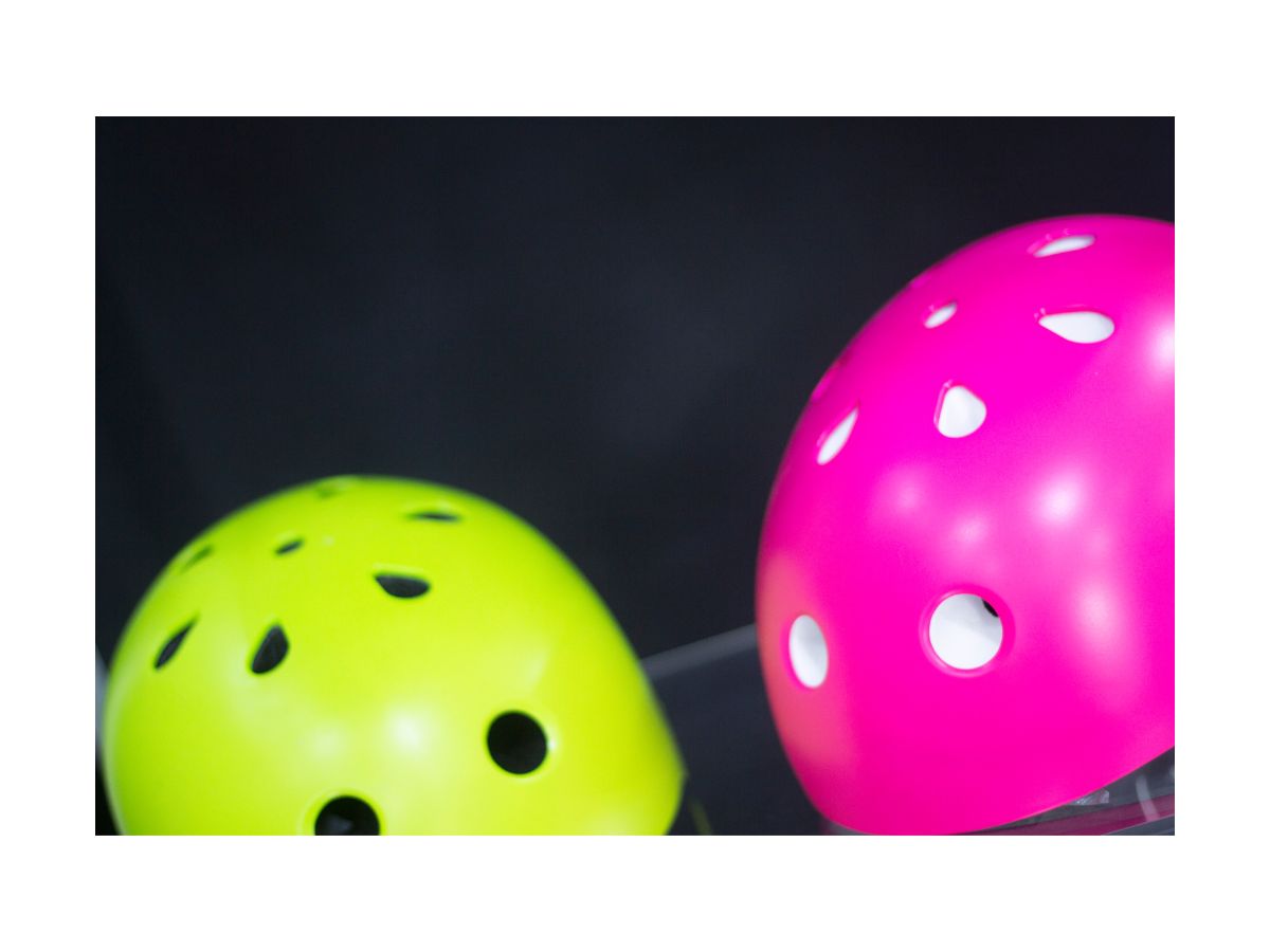 tops of roller derby helmets with one pink and one green helmet