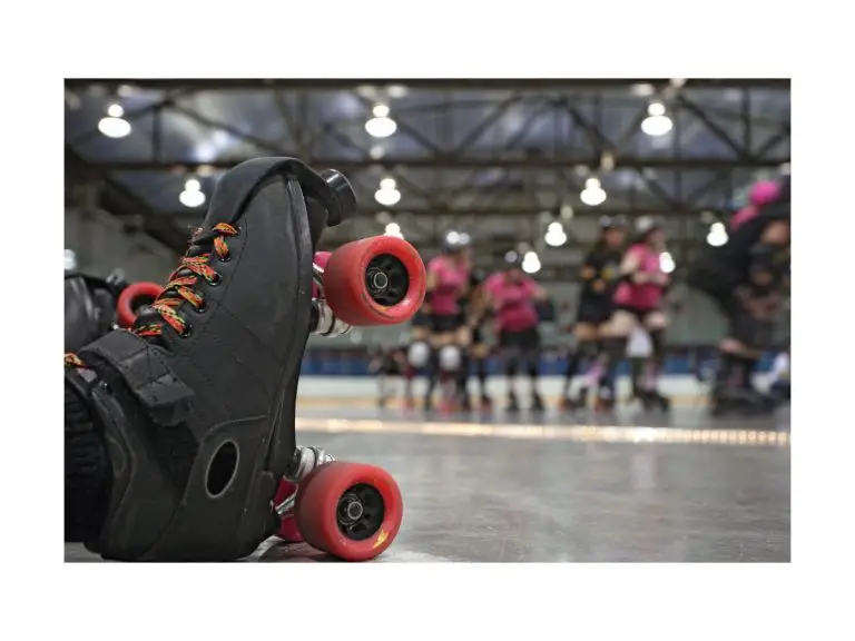 close up photo of roller skate resting one its heel with blurred roller derby players in background