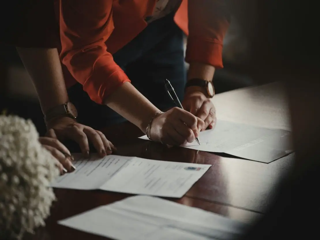 2 people filling out paper work on a dark table